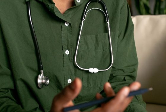 Close up torso shot of doctor wearing a dark green shirt with a stethoscope around his neck
