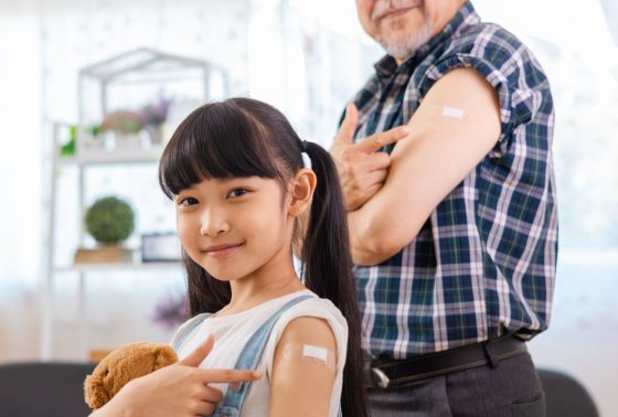 Elderly Man and Little Girl Pointing at Their Vaccinated Arm